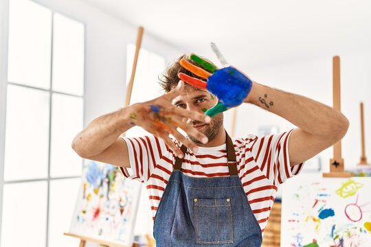 Young hispanic man smiling confident doing picture gesture with hands at art studio