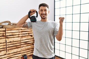 Young handsome man wearing sportswear using dumbbells screaming proud, celebrating victory and success very excited with raised arms