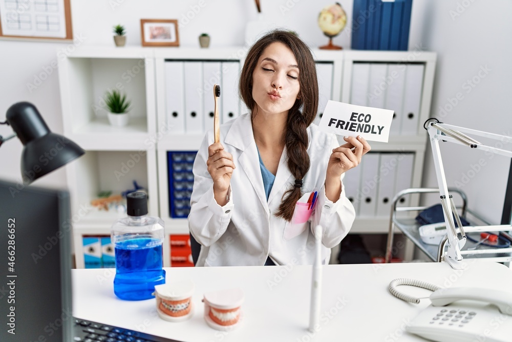 Poster young dentist woman holding eco friendly toothbrush looking at the camera blowing a kiss being lovel