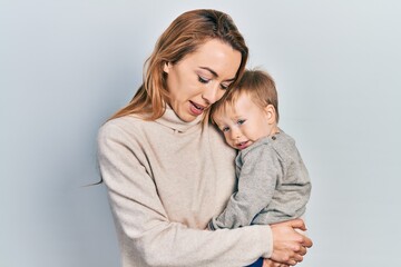 Young caucasian woman holding and hugging her son with love. Family of two bonding together. Mother holding infant toddler