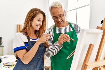 Fototapeta premium Middle age paint teacher and student smiling happy painting at art studio.