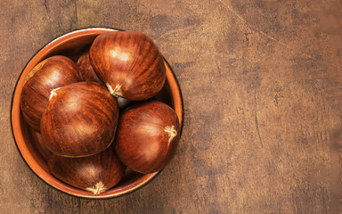 Sweet chestnuts on old rustic wooden table with plenty of copy space. Autumn fall concept. Horse chestnuts top view.