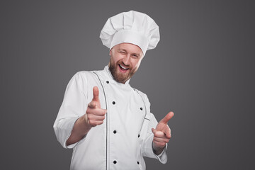 Cheerful chef pointing at camera and winking