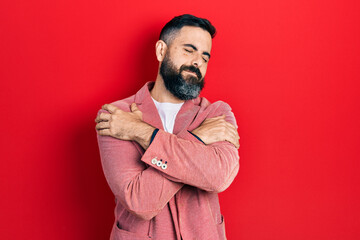 Young hispanic man wearing business clothes hugging oneself happy and positive, smiling confident. self love and self care