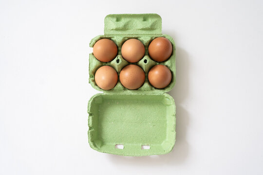 Des œufs bio dans leur boîte sur fond blanc
