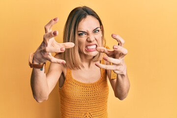 Young caucasian blonde woman wearing casual yellow t shirt shouting frustrated with rage, hands...