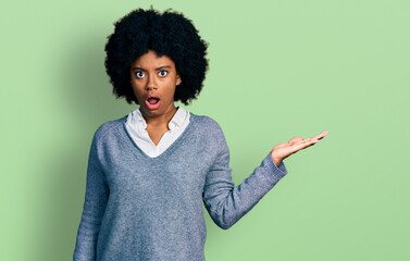 Young african american woman presenting with open palm in shock face, looking skeptical and sarcastic, surprised with open mouth