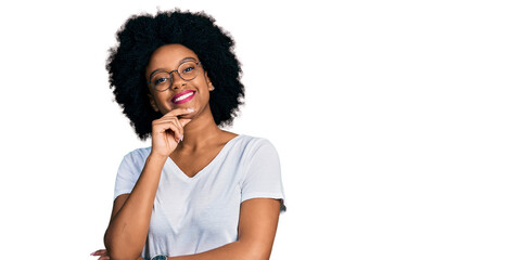 Fototapeta na wymiar Young african american woman wearing casual white t shirt looking confident at the camera smiling with crossed arms and hand raised on chin. thinking positive.