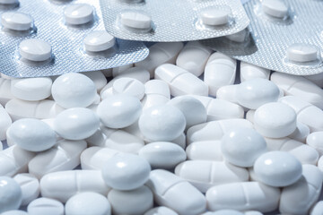 Closeup of white pills in blister packaging against white background.