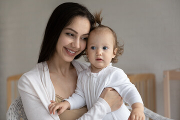 Head shot close up happy loving young mother hugging small daughter, smiling caring mom holding adorable little girl child toddler, family enjoying tender moment at home, motherhood concept