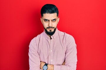 Handsome man with beard wearing casual red shirt skeptic and nervous, disapproving expression on face with crossed arms. negative person.