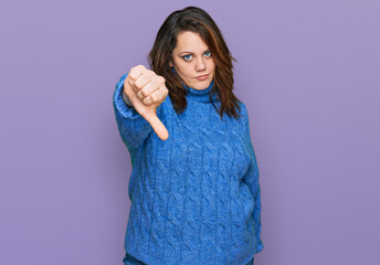 Fototapeta premium Young plus size woman wearing casual clothes looking unhappy and angry showing rejection and negative with thumbs down gesture. bad expression.
