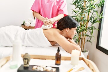 Obraz na płótnie Canvas Middle age hispanic woman smiling confident having back massage using thai bags at beauty center