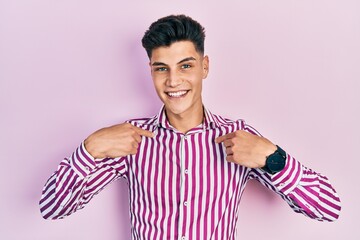 Young hispanic man wearing casual clothes looking confident with smile on face, pointing oneself with fingers proud and happy.