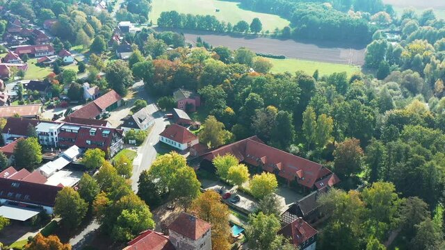 Aerial view of manor on the edge of village between tall trees in Germany