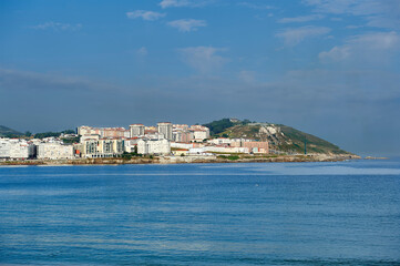 Obraz premium residential buildings and apartments in the Orzan cove in La Coruña with morning fog and the San Pedro mountain in the background