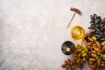 Two Wine bottles with grapes and wineglasses on old gray concrete table background with copy space. Red wine with a vine branch. Wine composition on rustic background. Mock up.