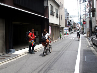 Travelers thai man backpacker walking travel visit and life lifestyle of japanese people ride bike bicycle in small alley street of Gion district at Kyoto city on July 11, 2015 in Kansai region, Japan