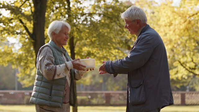 Charity and social welfare. Volunteer man giving a hot meal to an elderly woman. High quality 4k footage