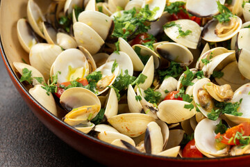 White shell clams with garlic, tomatoes and parsley white wine sauce in the fry pan