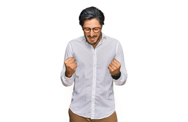 Young hispanic man wearing business shirt and glasses very happy and excited doing winner gesture...