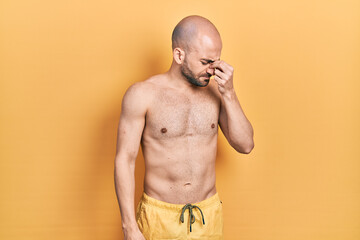 Fototapeta premium Young bald man wearing swimwear tired rubbing nose and eyes feeling fatigue and headache. stress and frustration concept.
