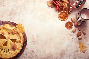 Halloween food. Homemade pumpkin pie or tart with a scary face for Halloween on a wooden table. Copy space. Halloween food concept.