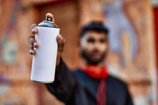 Young arab man relaxed holding graffiti spray at street