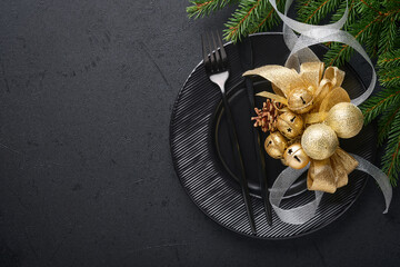 Served christmas table setting empty black ceramic plate on dark background Christmas Decoration. Holiday Decorations with gold baubles and fir branches on dark black background Border design Top view - Powered by Adobe