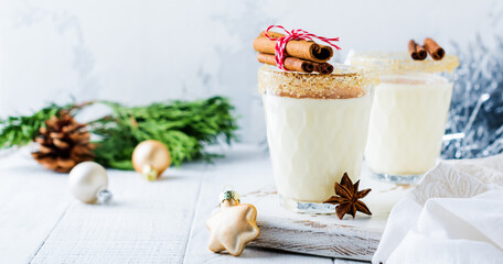 Eggnog Traditional Christmas drink milkshake with cinnamon on light old background. Selective focus.