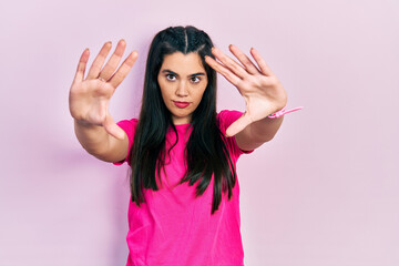 Young hispanic girl wearing casual pink t shirt doing frame using hands palms and fingers, camera perspective