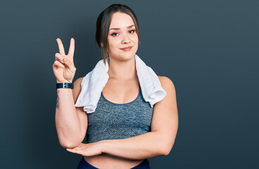 Young hispanic girl wearing sportswear and towel smiling with happy face winking at the camera...