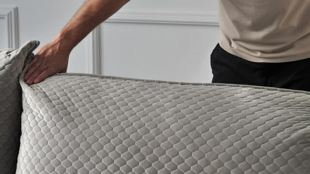 Man touching soft pillows on sofa with his hands. Furniture store