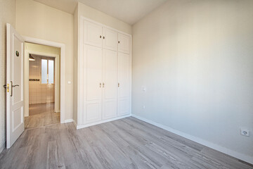 Room with gray wooden floors with built-in wardrobe with cream white lacquered carpentry