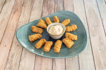 White fish croquettes battered with eggs, flour and parsley with aioli sauce for dipping on a blue...