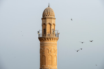 Top of a red sandstone minaret with speakers for the call to prayer and birds nestled in the dome...