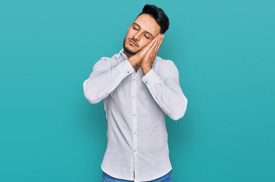 Young arab man wearing casual clothes sleeping tired dreaming and posing with hands together while smiling with closed eyes.