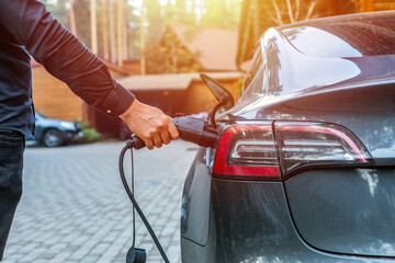 man connecting a charging cable to a car from an electric car charging station. Electric car charging with station, EV fuel advance and modern eco system, Save the earth conception.
