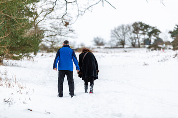 An unknown couple taking a walk through a snowy countryside landscape