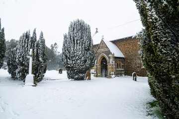 All Saints church in the small village of Sutton in the British countryside, it is totally covered in deep snow during a rare snow storm in the UK