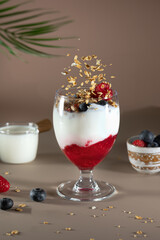 Bowl of granola with yogurt, milk and fresh raspberries, blueberries, mango for a healthy breakfast on the dark background
