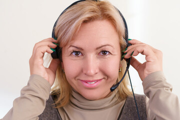 Close-up portrait of smiling middle-aged caucasian woman adjusting a headset on her head.