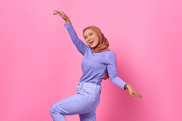 Portrait of beautiful young Asian woman dancing happy and cheerful on pink background