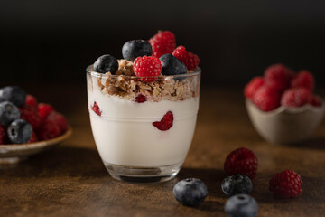 Bowl of granola with yogurt, milk and fresh raspberries, blueberries, mango for a healthy breakfast...