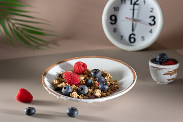 Bowl of granola with yogurt, milk and fresh raspberries, blueberries, mango for a healthy breakfast on the dark background