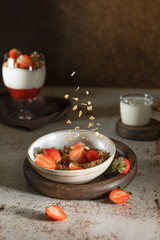 Bowl of granola with yogurt, milk and fresh raspberries, blueberries, mango for a healthy breakfast on the dark background