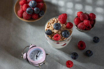 Bowl of granola with yogurt, milk and fresh raspberries, blueberries, mango for a healthy breakfast on the dark background