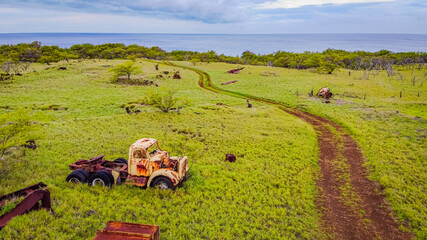 A yellow rusty car in the background of the sea. Road on a volcanic landscape. Amazing scenery. Hawaii.