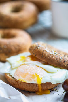 Fresh healthy bagel sandwich with sunny side up fried egg with black coffee. Healthy diet food. Selective focus with blurred background.