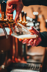 bartender hand at beer tap pouring a craft beer in glass serving in a bar or pub